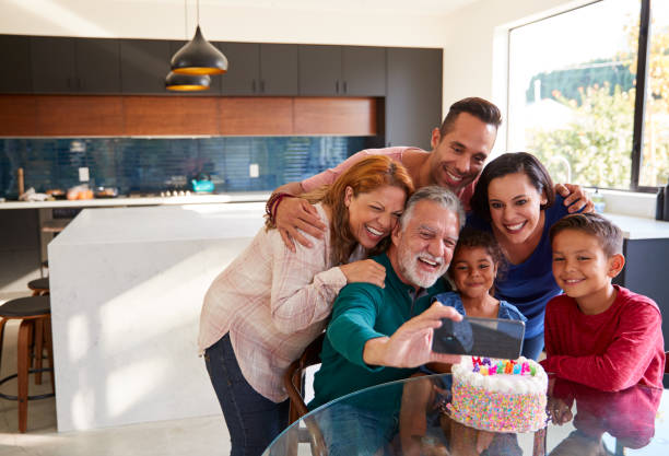 famiglia ispanica multi-generazione che si fa selfie per festeggiare il compleanno delle nipoti a casa - wireless technology cheerful granddaughter grandmother foto e immagini stock