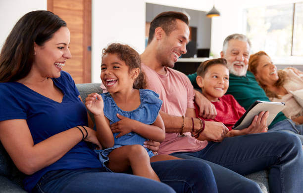 multi-generation hispanic family entspannen auf sofa als enkel spielt mit digitalen tablet - grandparent multi generation family grandfather child stock-fotos und bilder