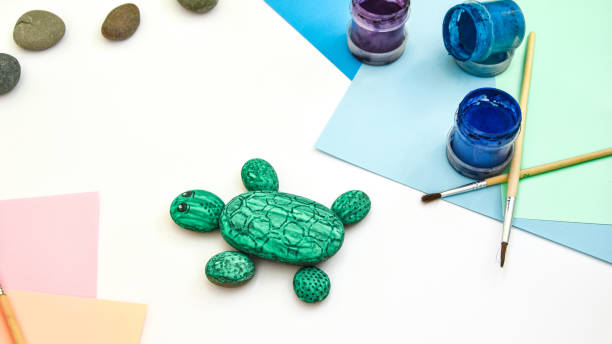 Step 6 Painting a stone green turtle on a stone step by step. Children art project. DIY concept. Step by step photo instruction. View from above. Work with children and adults in quarantine.