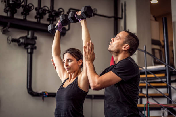 istock Young beautiful female working out in gym with personal trainer 1224788672