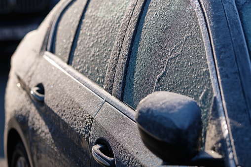 Detail of a frozen car on a cold and sunny winter morning covered with ice. Seen in Germany in January.