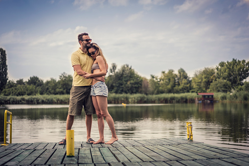 Man hugging woman next to lake