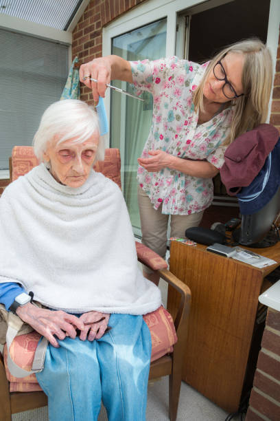 l'anziana ha i capelli tagliati dalla sua badante durante il blocco del virus corona a casa. - housebound foto e immagini stock