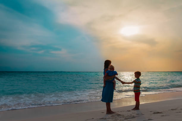istock mother with two kids walking on beach at sunset 1224796439