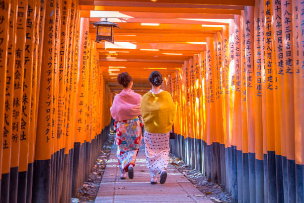 Fushimi Iniari Shrine in Kyoto, Japan Kyoto, Japan - December 13, 2014: Two geishas walking through orange gates called torii at the Fushimi Inari Shrine shinto photos stock pictures, royalty-free photos & images