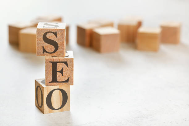 istock Three wooden cubes with letters SEO (means Search Engine Optimization), on white table, more in background, space for text in right down corner 1224799865
