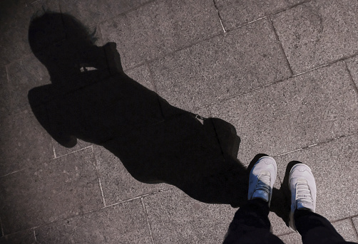 When looking down at the shadow of a woman on a concrete road. Diagonal