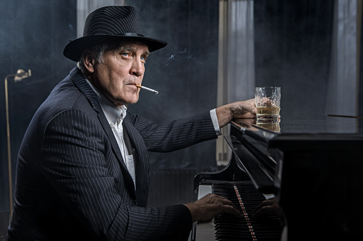 Senior Gangster man playing the piano in a jazz club setting