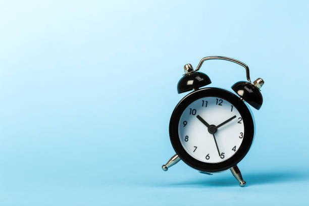 istock black vintage alarm clock falling on the blue floor 1224804684