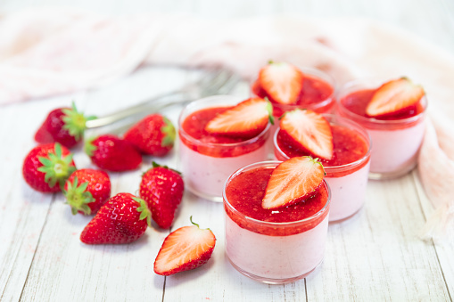 Homemade strawberry mousse in a glass on an old white rustic wooden table