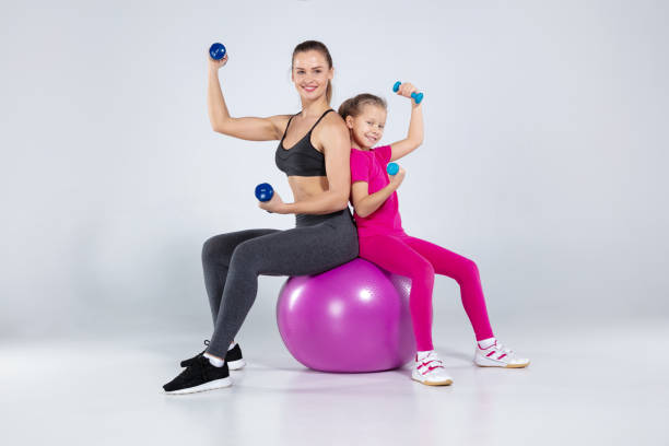 Athletic woman and nice girl doing sport exercises stock photo