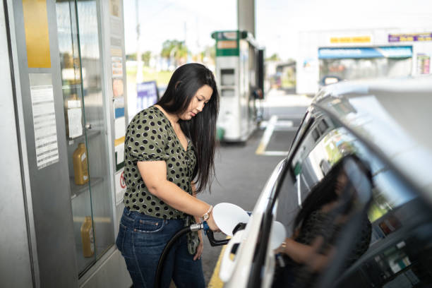 молодая женщина заправляет свой автомобиль на заправке - gasoline filling gas station car стоковые фото и изображения