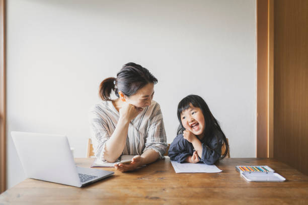 Mother working from home with daughter Asian mother is  working with laptop in the living room and her daughter is drawing pictures. child candid indoors lifestyles stock pictures, royalty-free photos & images