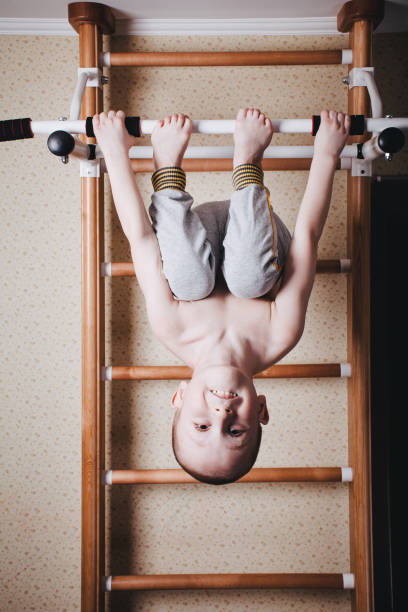 heimtraining. der junge hängt mit dem kopf nach unten auf der horizontalen leiste - kletterwand turngerät stock-fotos und bilder