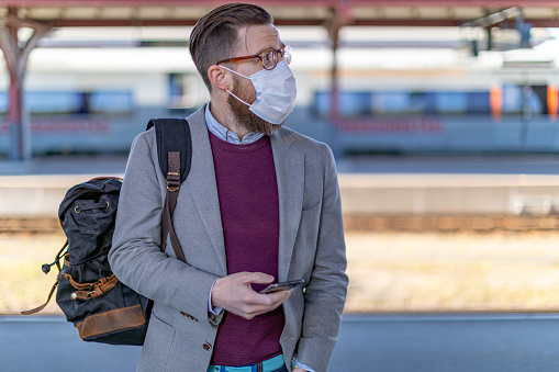 A businessman wearing protective face mask waiting for the train
