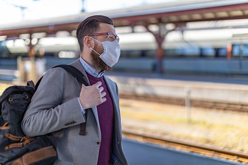 A businessman wearing protective face mask waiting for the train