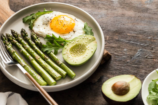 Healthy homemade breakfast with asparagus, fried egg, avocado and arugula. quarantine healthy eating concept. keto diet stock photo