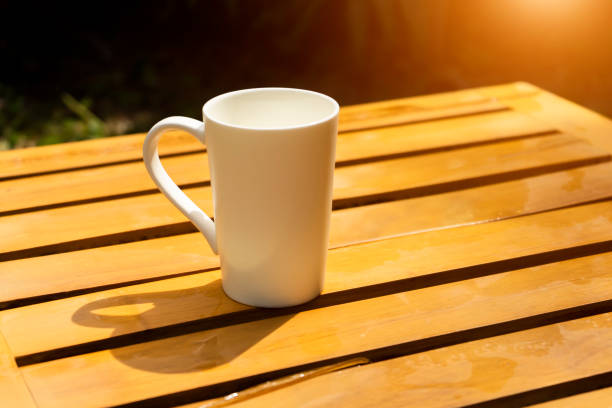 White Coffee mug in the morning time on wood with sunlight.