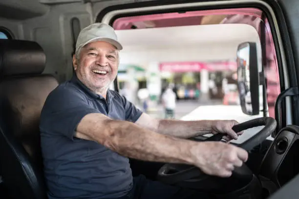 Photo of Portrait of a senior male truck driver sitting in cab