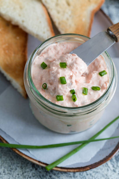 Salmon and soft creme cheese spread in jar. Salmon rillettes, mousse, pate and toasts on gray background Salmon and soft creme cheese spread in jar. Salmon rillettes, mousse, pate and toasts on gray background tuna pate stock pictures, royalty-free photos & images