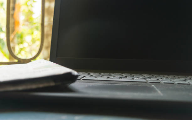 close up newspaper placed on laptop keyboard. morning sunlight coming from window. media information medium and wireless technology background concept. - the media newspaper paper information medium imagens e fotografias de stock