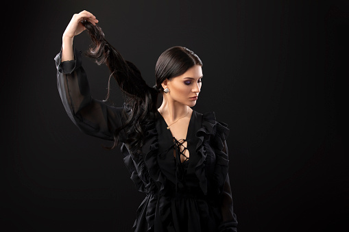 strong healthy hair - Woman holds a pony tail over black background. Fashion portrait of female model