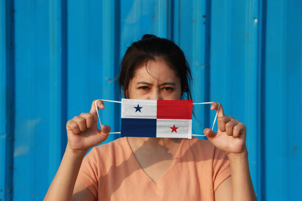 una mujer con bandera de panamá en máscara higiénica en la mano y levantó la cara frontal sobre fondo azul. diminuta partícula o virus corona o covid 19 protección. - arms lifted fotografías e imágenes de stock