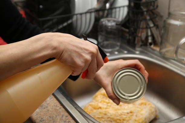 istock A women sanitizing canned goods in a kitchen sink. 1224815452