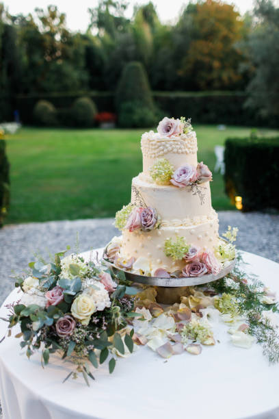 istock Wedding cake standing on the table. Around the flowers. 1224818190