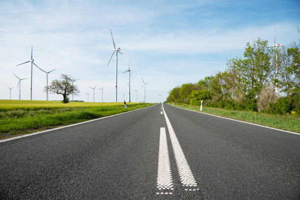 On the country road between fields with wind turbines