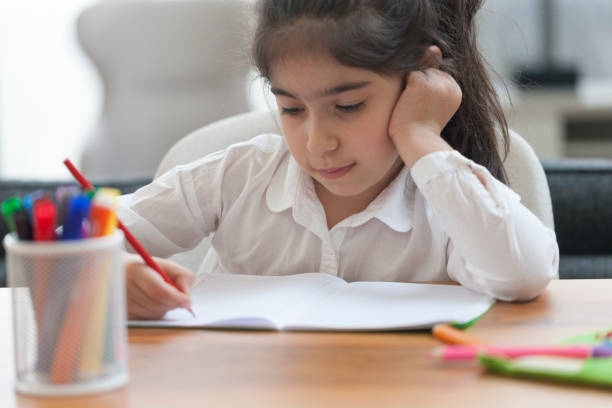 istock Cute little girl sitting at the table doing his homework 1224822313