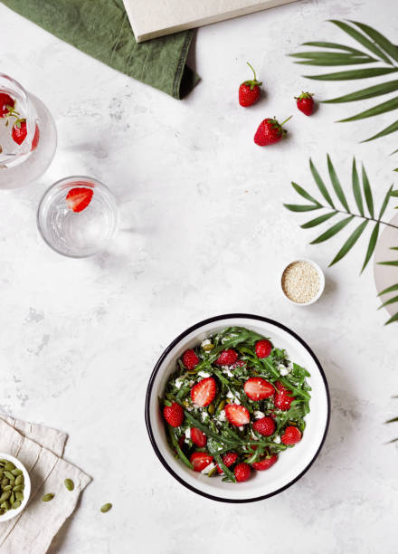 sommersalat aus frischer erdbeere, fetta-käse, rucola, kürbis und sesamsamen auf weißem hintergrund flach liegen. - fetta cheese fotos stock-fotos und bilder