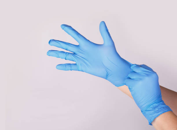 Doctor or nurse putting on blue nitrile surgical gloves, professional medical safety stock photo