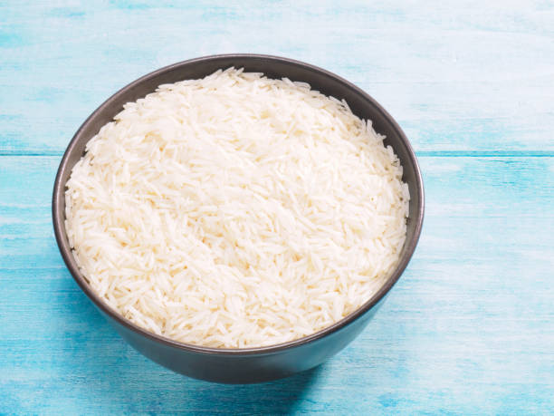 istock Long grain Basmati rice in brown ceramic bowl on blue wooden background 1224828026