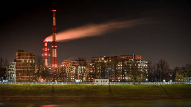 nocny widok na dym wydobywający się z komina nad blokami mieszkalnymi w mieście. - wroclaw traffic night flowing zdjęcia i obrazy z banku zdjęć