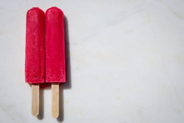 istock Two red pink popsicles sitting on a white marble slab 1224828669