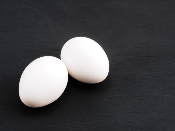 istock Two white chicken eggs on a black wooden background. Healthy eating concept 1224829443