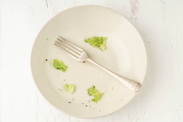 Food leftovers on dirty plate after finished salad stock photo
