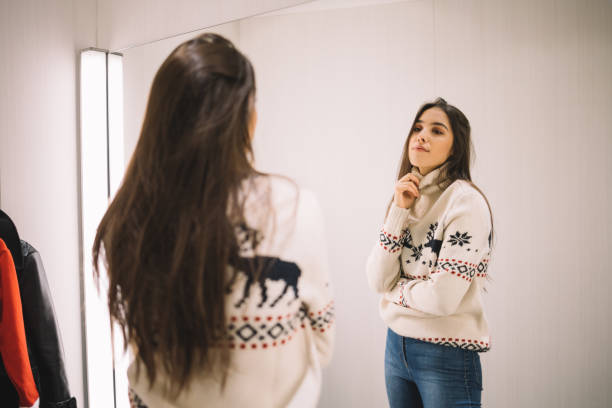 istock Thin woman in sweater looking into a mirror 1224829818