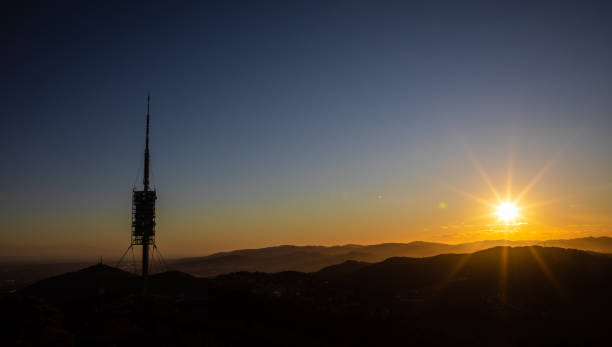 istock Big telecommunications antenna silhouette on the hills during sunset with sun rays 1224835838