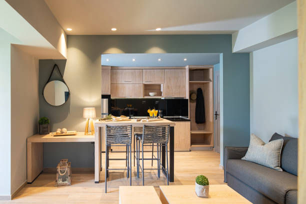 modern grey and wooden interior of small studio apartment. front view of hotel flat room witn kitchen, living, bedroom in single space - greece blue house wall imagens e fotografias de stock