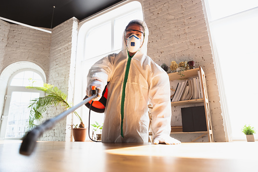 Pandemia de Coronavirus. Un desinfectante en traje protector y máscara pulveriza desinfectantes en la casa u oficina photo