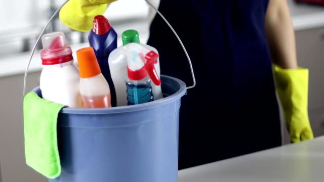 Woman walks into room with cleaning equipment and places bucket on table