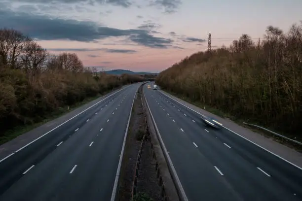 A motorway in the UK, during the Covid 19 lock down. It is early evening, during rush hour, and the motorway is almost deserted