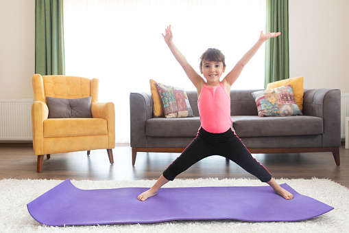 Toddler beautiful girl practice yoga at home.