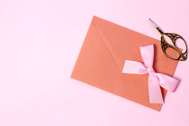 istock An envelope with a pink bow, a gold ring on a pastel pink background. Flat lay style. 1224848346
