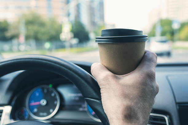 istock Elderly Businessman drinking coffee from paper cup while driving a car on the highway. Selective focus 1224849476