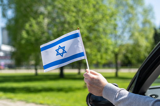 Man holding Israel flag from the open car window. Concept