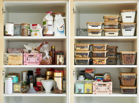 A middle-aged woman tidies up her cupboard in the kitchen and reorganizes everything to make a comparison before and after