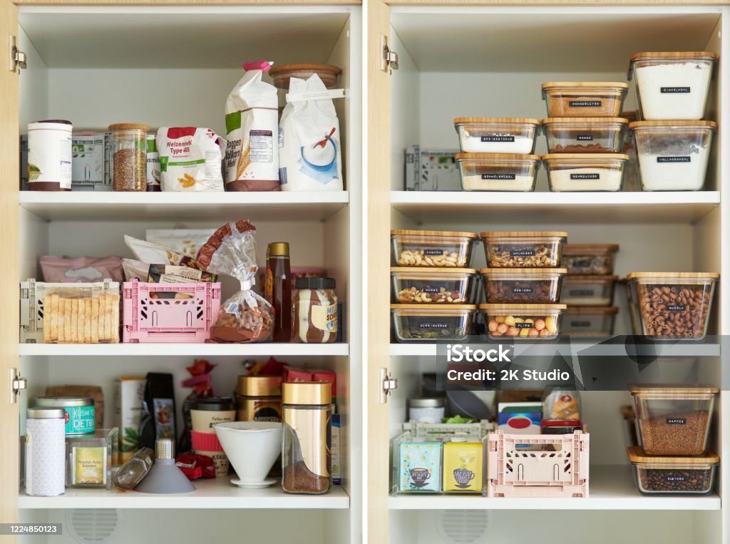 A middle-aged woman tidies up her cupboard in the kitchen and reorganizes everything A middle-aged woman tidies up her cupboard in the kitchen and reorganizes everything to make a comparison before and after Cabinet Stock Photo